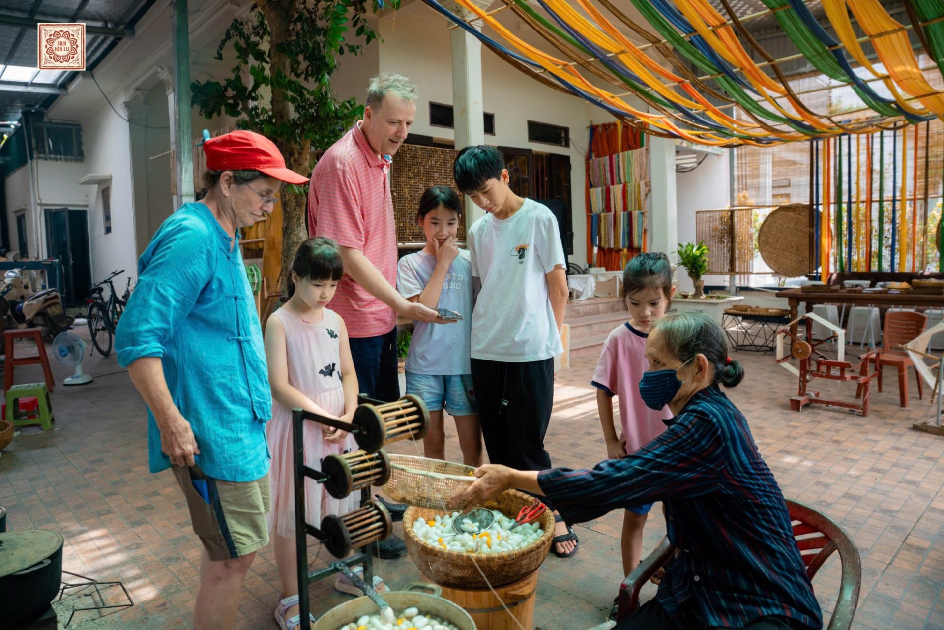 Besucher beobachten das Abhaspeln von Seide aus Kokons in Silk Hoa Lu Ninh Binh