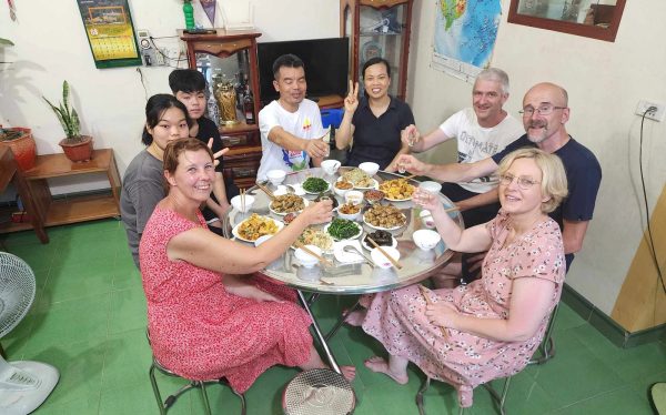 Guests and a local family toasting at a home dinner near Ninh Binh