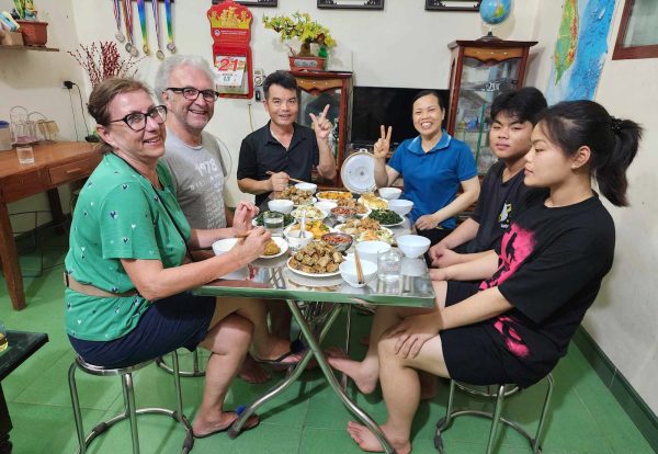 Travellers and a Vietnamese family sharing dinner at home in Ninh Binh