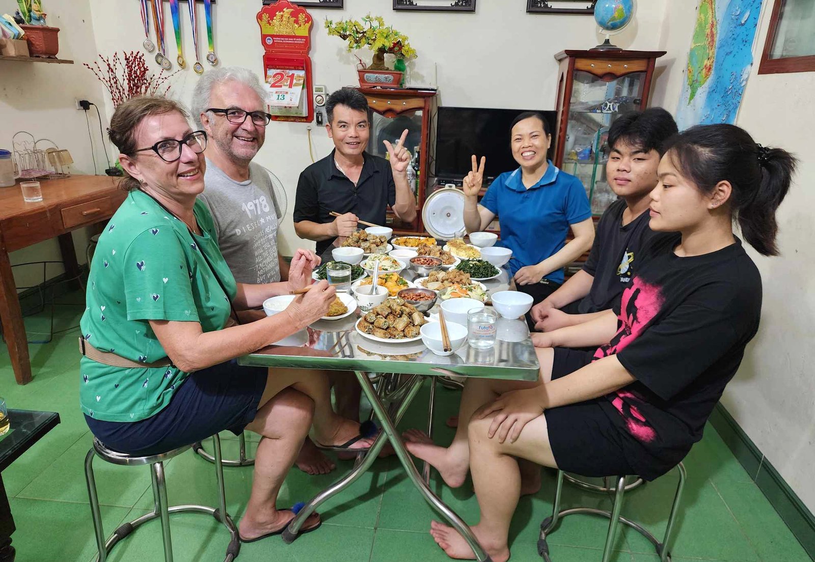 Travellers and a Vietnamese family sharing dinner at home in Ninh Binh
